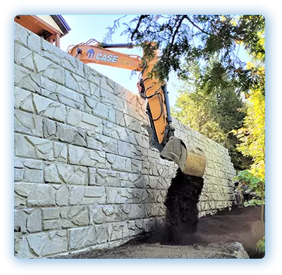 Construction d’un mur de soutènement en Estrie par les Entreprises Talbot – Excavation et remblaiement avec une pelle mécanique à Sherbrooke pour stabilisation de terrain résidentiel.